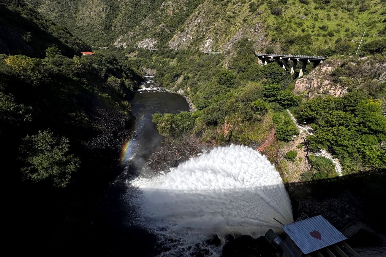 El Dique San Roque y una postal de su estado de agua por sobre el nivel del vertedero. Turistas mirando la cola de novia y el espectáculo del embudo. (La Voz) 