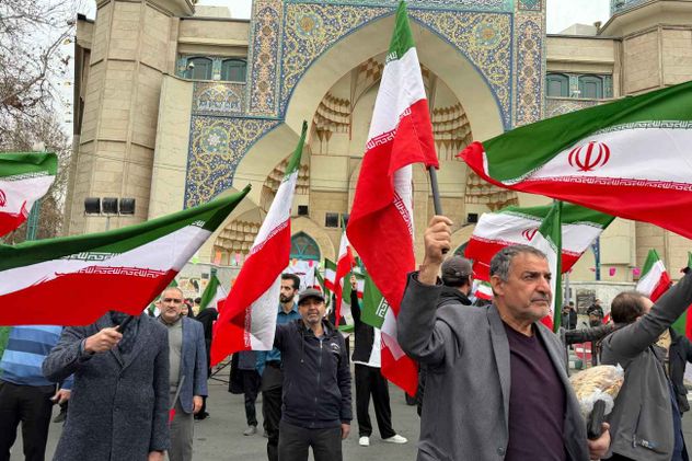 Un grupo de hombres ondea banderas iraníes durante una manifestación en apoyo al gobierno y contra los ataques estadounidenses e israelíes en Teherán, Irán, el sábado 28 de febrero de 2026. 