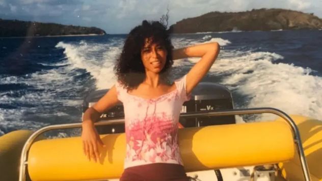 Lisa Phillips en un barco con la isla de Epstein al fondo.