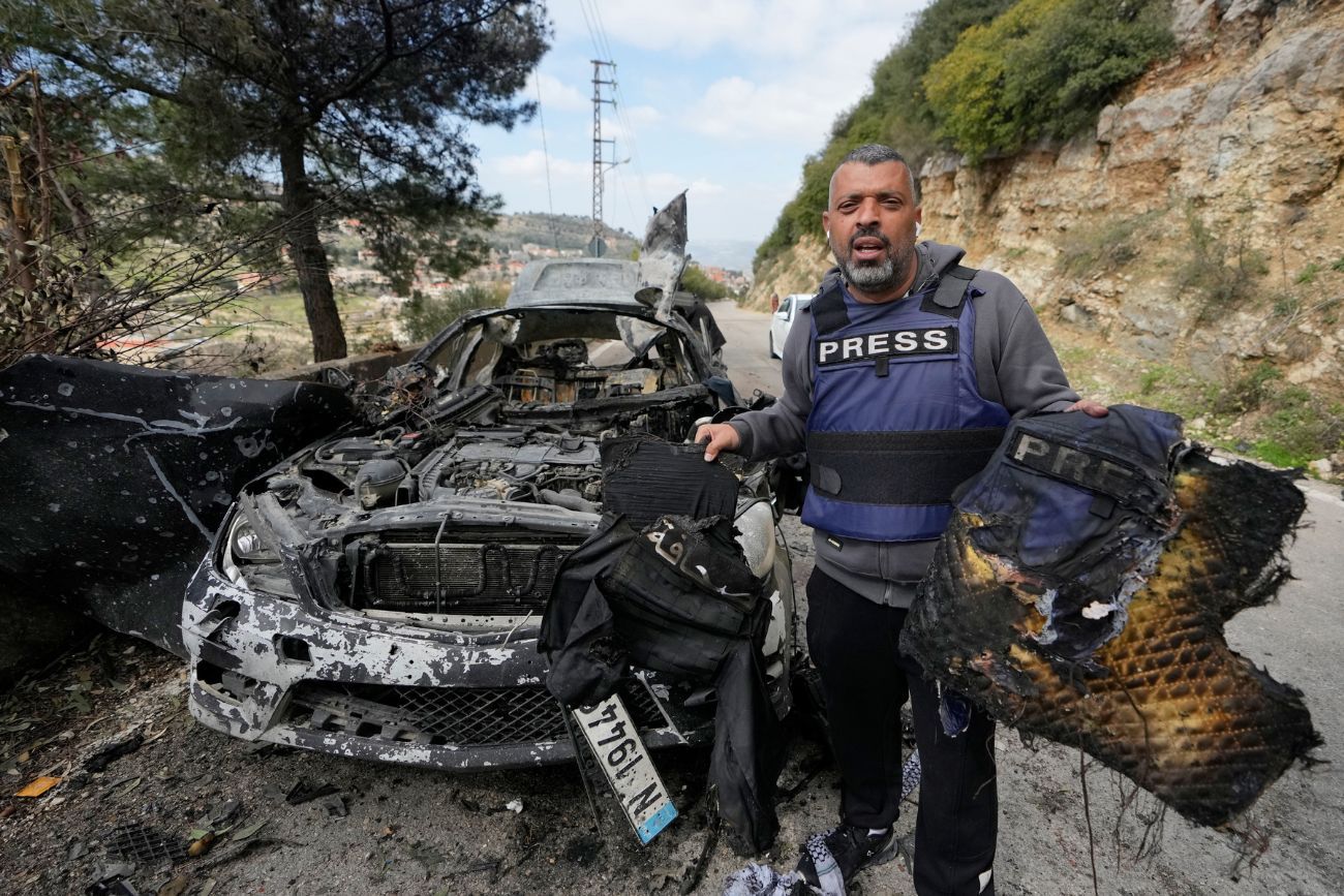 Un periodista transporta equipo de seguridad quemado tras un ataque aéreo israelí contra un automóvil que acabó con la vida de tres periodistas. (Foto AP/Mohammed Zaatari)