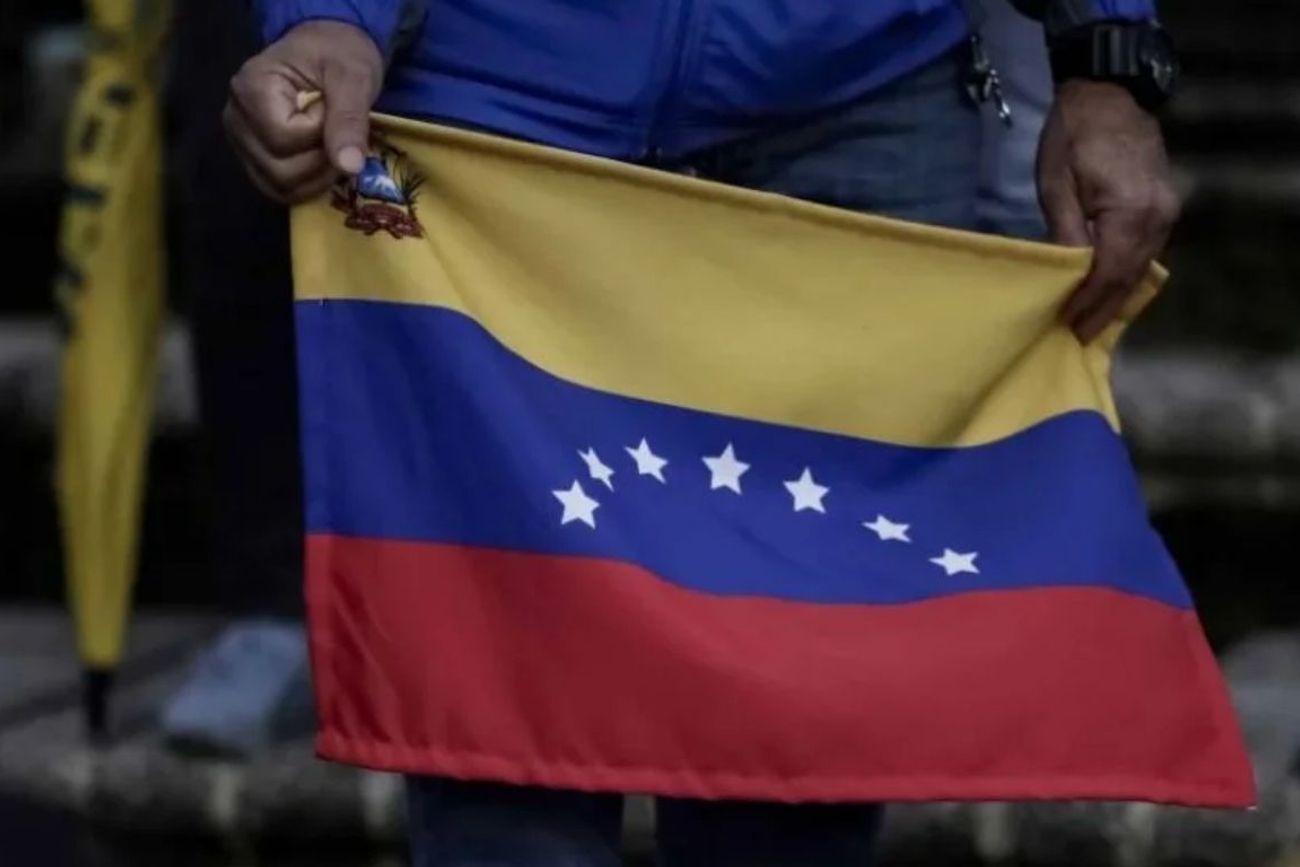 Un hombre sostiene una bandera venezolana. 