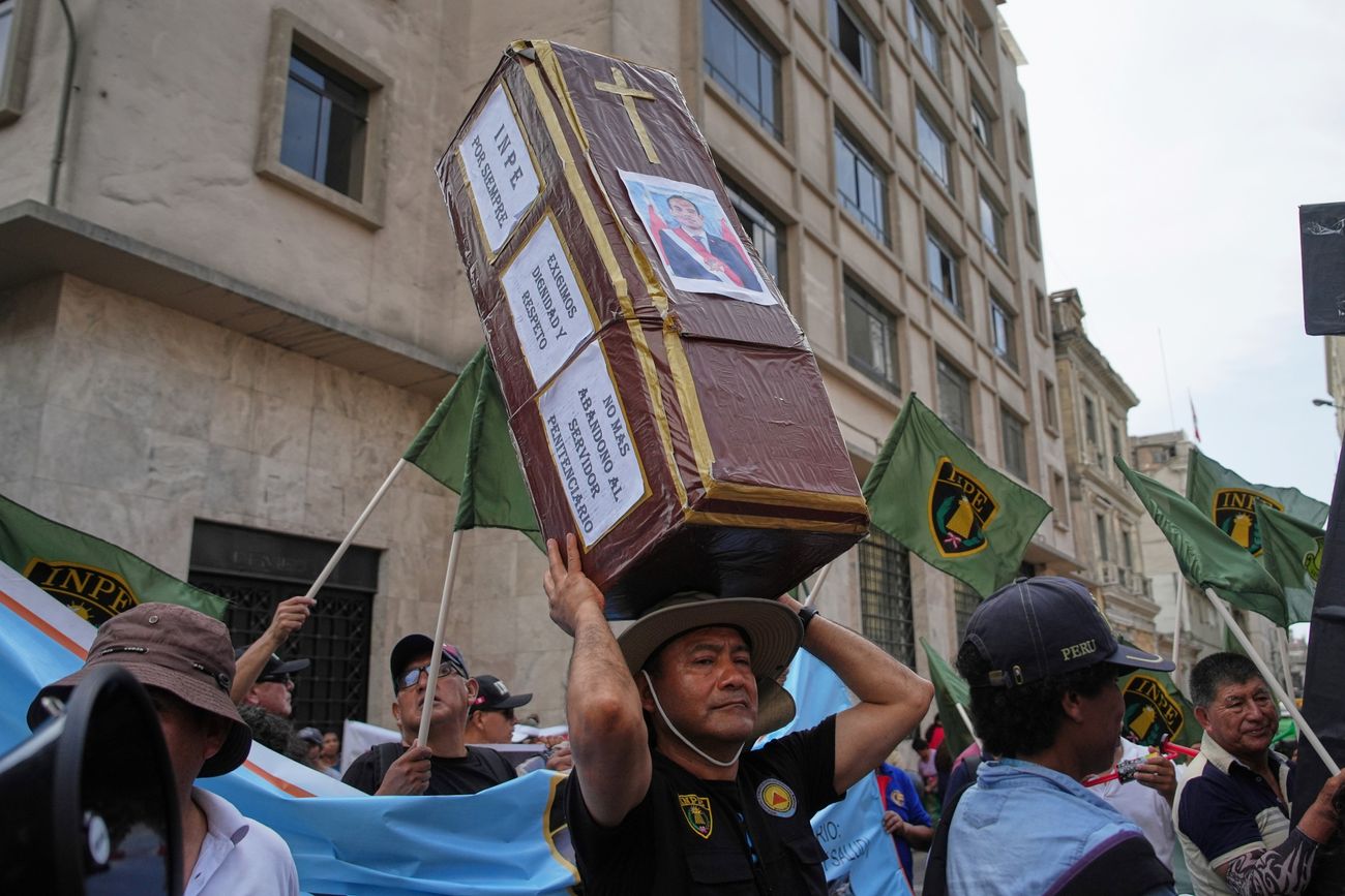 Perú: un manifestante sostiene un ataúd con la imagen del expresidente destituido José Jeri. 