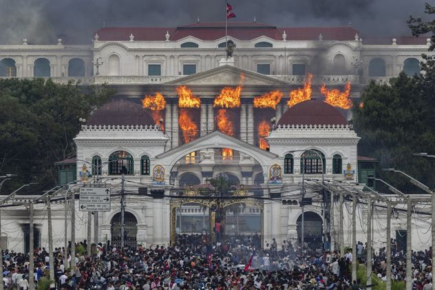 2- El Singha Durbar arde tras ser tomado e incendiado por manifestantes durante violentas protestas en Katmandú, Nepal; fuego y humo envuelven el complejo gubernamental. 