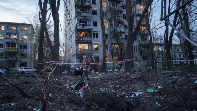 Una mujer camina con su perro entre los escombros de una vivienda dañada en Kiev. El ataque destruyó al menos 17 edificios de apartamentos en la capital. (AP Photo/Evgeniy Maloletka)