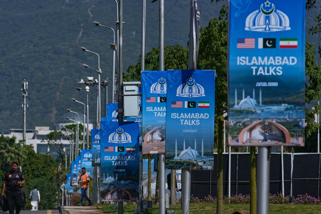 Trabajadores pasan junto a carteles publicitarios cerca del Hotel Serena antes de la segunda ronda de negociaciones entre Estados Unidos e Irán, en Islamabad, Pakistán, lunes 20 de abril de 2026. (Foto AP/Anjum Naveed)