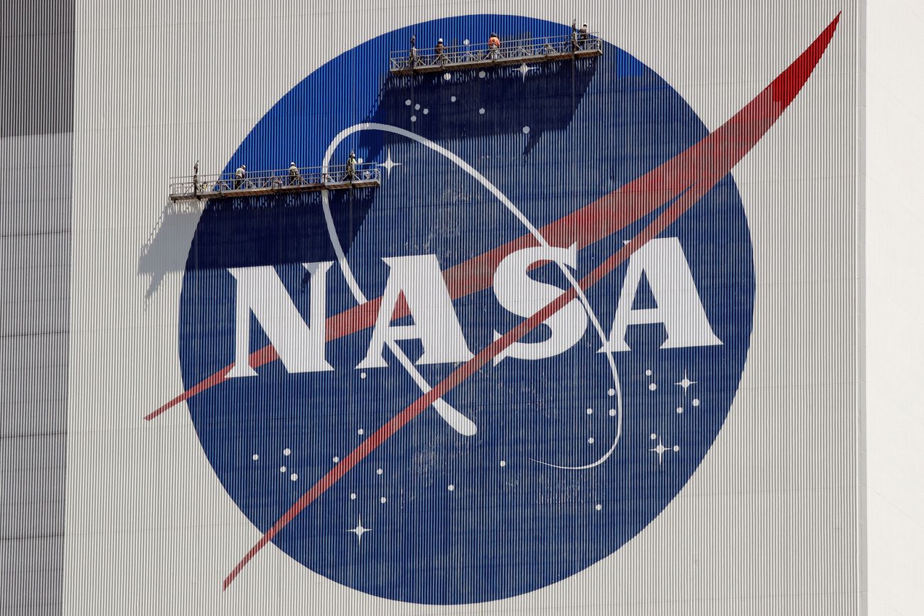 Trabajadores sobre andamios repintan el logotipo de la NASA cerca de la parte superior del Edificio de Ensamblaje de Vehículos en el Centro Espacial Kennedy en Cabo Cañaveral, Florida, el 20 de mayo de 2020. (Foto AP/John Raoux, Archivo)
