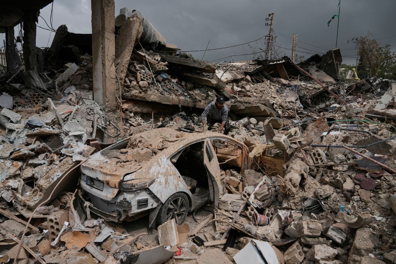 Un hombre inspecciona su coche dañado entre los escombros de las tiendas destruidas en anteriores ataques aéreos israelíes en el barrio de Hosh, en Tiro, al sur del Líbano, el 19 de abril de 2026.