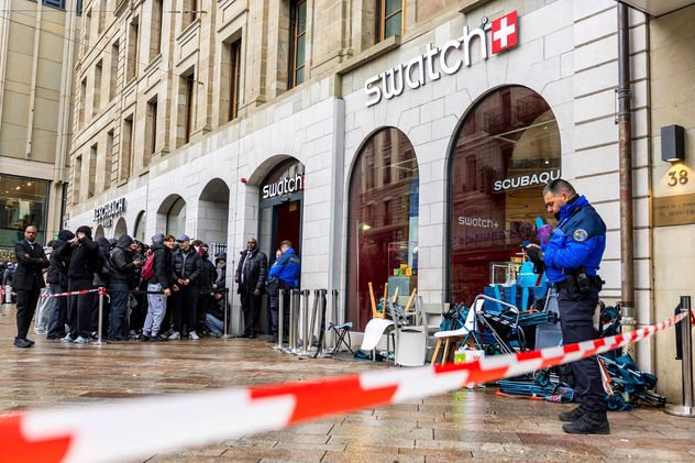 Agentes de policía suizos aseguran el área donde los clientes hacen cola para comprar el nuevo reloj Royal Pop, de Swatch y Audemars Piguet, en Ginebra, Suiza. (AP)