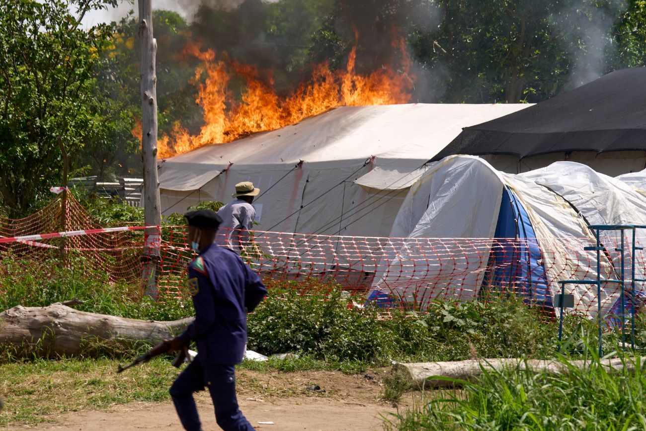 Un guardia de seguridad corre frente a un centro de tratamiento del ébola en llamas en Rwampara, Congo, el jueves 21 de mayo de 2026. 