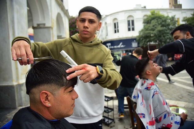 Peluqueros en el Cabildo de Córdoba. Jóvenes barberos ofrecen cortes a personas en situación de calle, en la Plaza San Martín. 