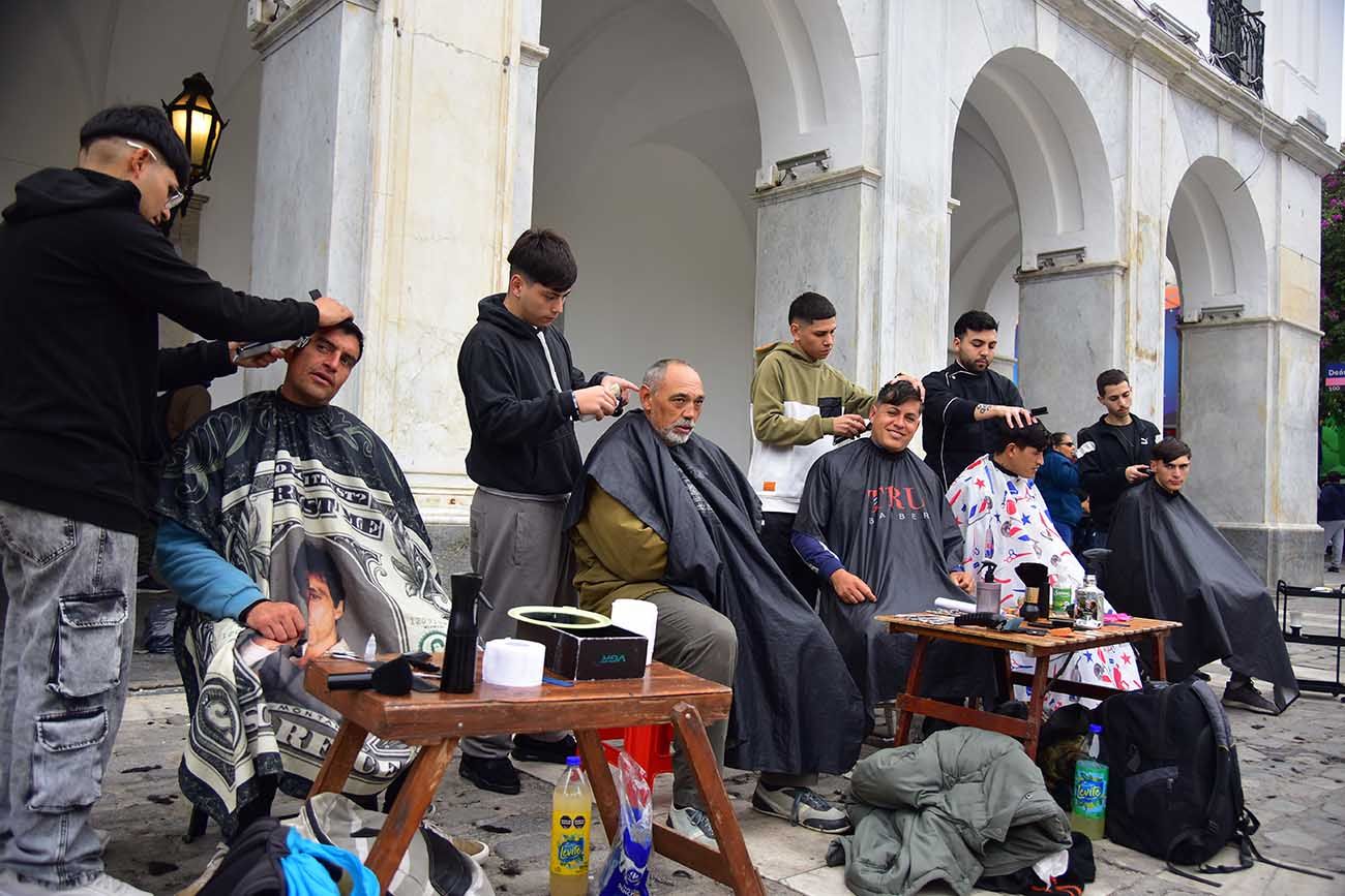 Peluqueros en el Cabildo de Córdoba. Jóvenes barberos ofrecen cortes a personas en situación de calle, en la Plaza San Martín. 
