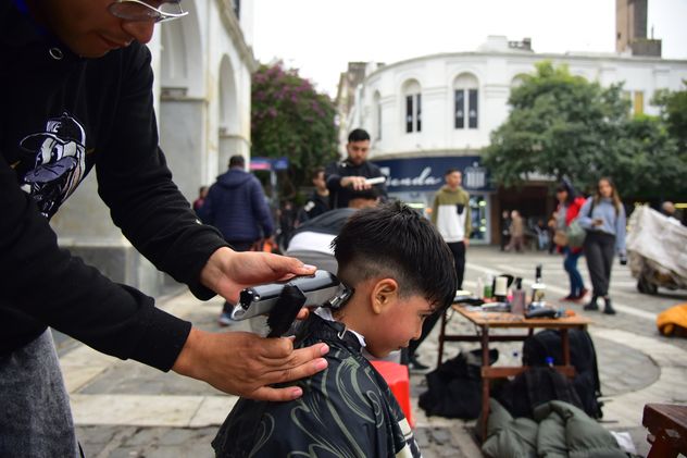 Peluqueros en el Cabildo de Córdoba. Jóvenes barberos ofrecen cortes a personas en situación de calle, en la Plaza San Martín. 