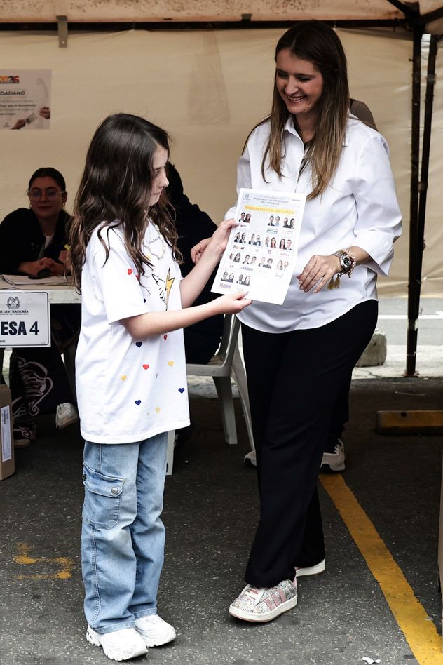 La candidata presidencial Paloma Valencia, del partido Centro Democrático, le muestra su boleta electoral a su hija durante las elecciones presidenciales en Bogotá, Colombia, el domingo 31 de mayo de 2026. (Foto AP/Jose Vargas)