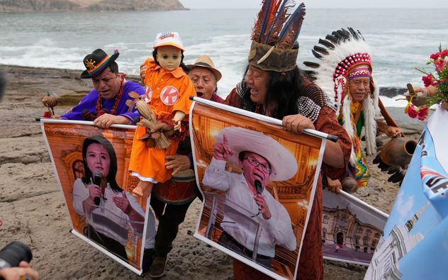 Chamanes realizan un ritual sosteniendo carteles de los candidatos que definirán la presidencia de Perú en balotaje, en la playa Herradura, en Lima. (Martín Mejía)
