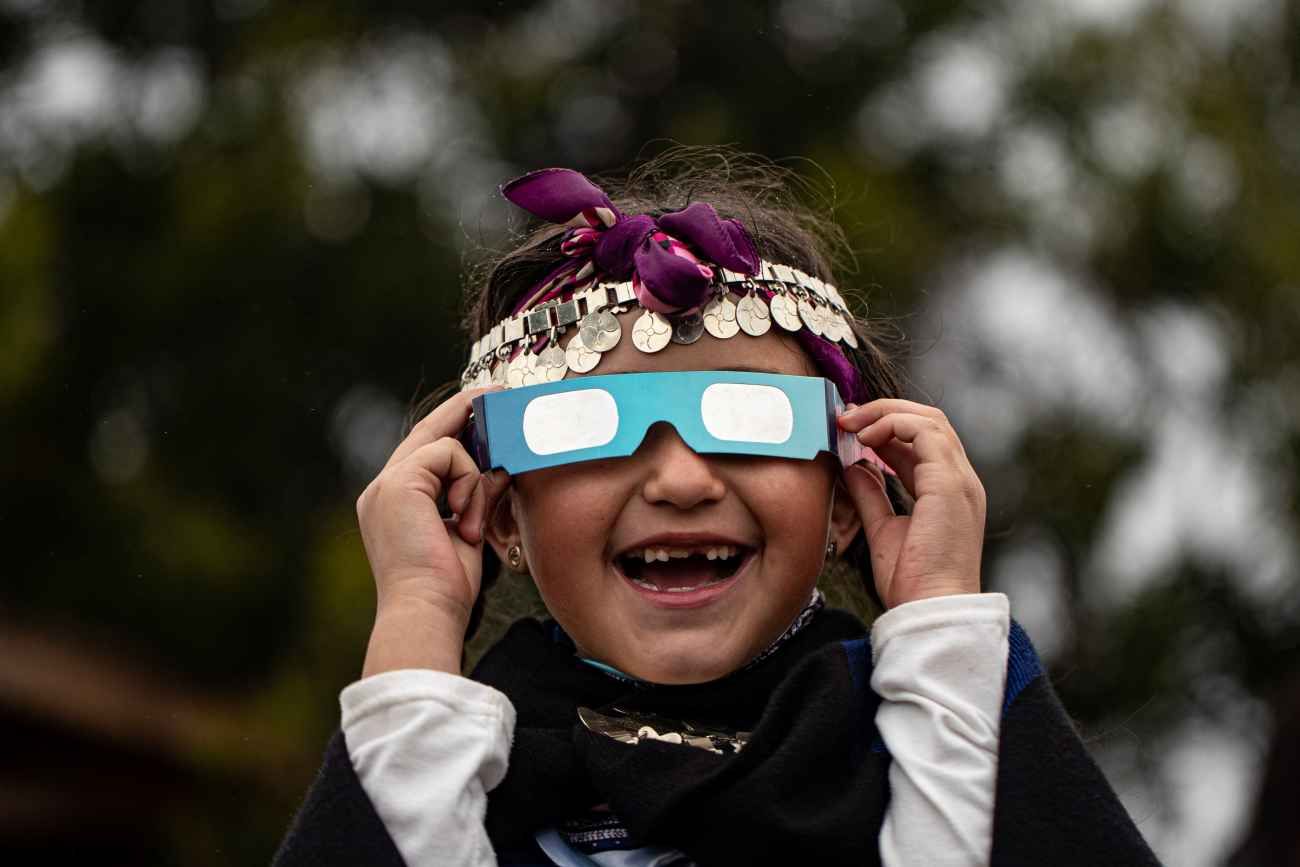 Magdalena Nahuelpan, una niña indígena mapuche, observa un eclipse solar total con gafas especiales en Carahue, La Araucanía, Chile.