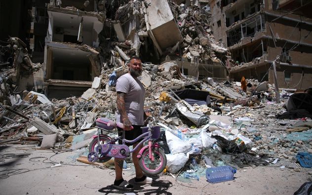 El barbero Wissam Srour, de 41 años, sostiene la bicicleta de su hija recuperada de su barbería mientras busca pertenencias entre los escombros de la tienda, dañada por un ataque israelí, en la ciudad portuaria sureña de Tiro, Líbano, el 19 de junio de 2026. (Hassan Ammar)