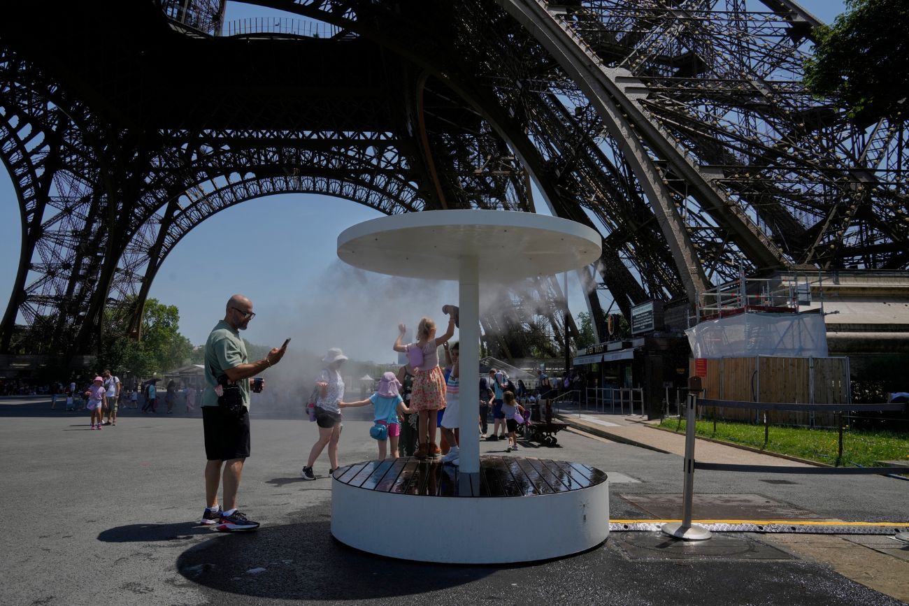 Varias personas se refrescan con un chorro de agua en la Torre Eiffel de París, el domingo 21 de junio de 2026.