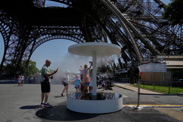 Varias personas se refrescan con un chorro de agua en la Torre Eiffel de París, el domingo 21 de junio de 2026. 