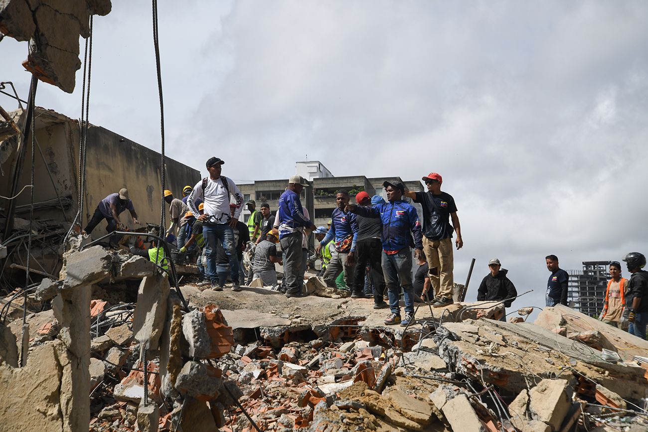 Trabajadores caminan frente un edificio derrumbado luego de que se registraran dos terremotos, en Caracas, Venezuela.