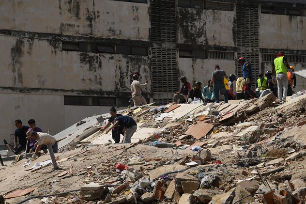 Trabajadores caminan frente un edificio derrumbado luego de que se registraran dos terremotos, en Caracas, Venezuela.