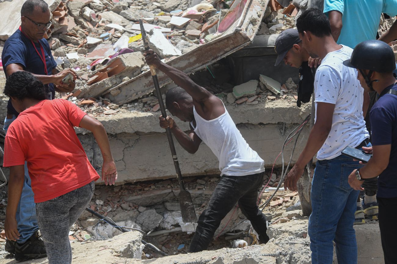 Personas remueven escombros de un edificio derrumbado en busca de sobrevivientes luego de que se registraran dos terremotos, en Playa Grande, estado La Guaira, Venezuela.