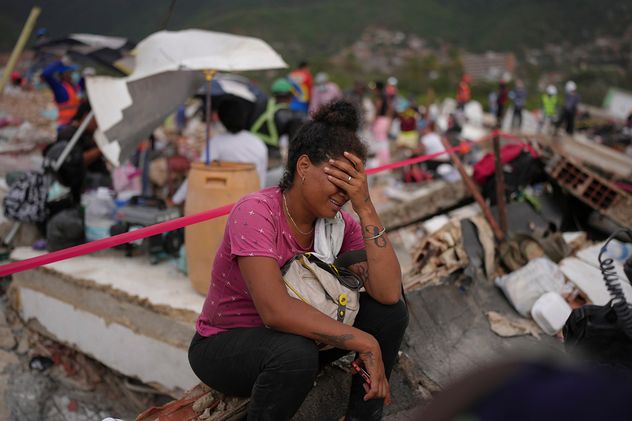 Khaterine Roa llora mientras miembros del Departamento de Bomberos del condado de Los Ángeles buscan sobrevivientes en un edificio que se derrumbó durante los terremotos que azotaron La Guaira, Venezuela.