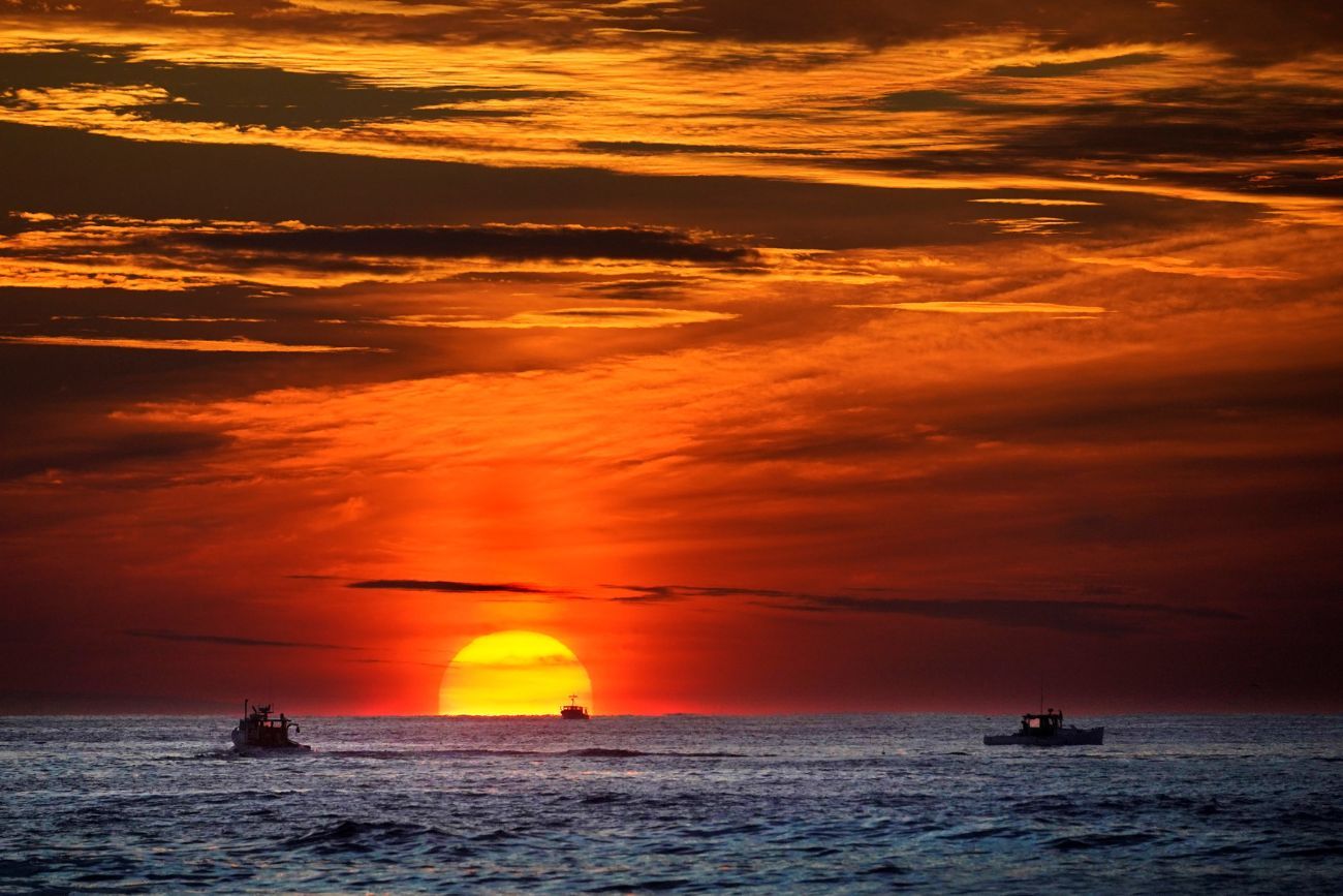 Pescadores de langosta trabajando mientras sale el sol sobre el océano Atlántico, frente a las costas de Kennebunkport, Maine. (Foto AP / Robert F. Bukaty)