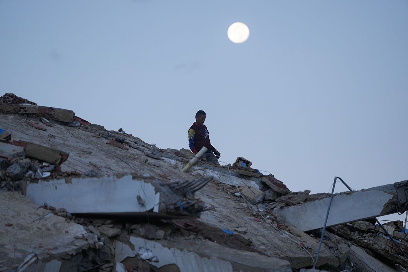 Grupos de rescatistas buscan entre los escombros de un edificio que se derrumbó en los terremotos ocurridos en La Guaira, Venezuela.
