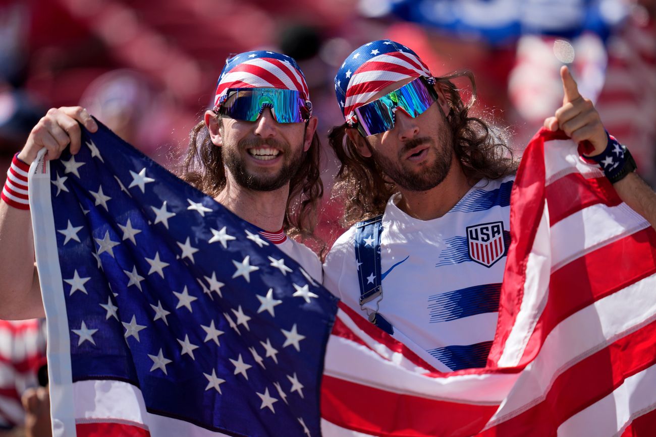Dos hermanos sostienen la bandera de Estados Unidos en la tribuna.