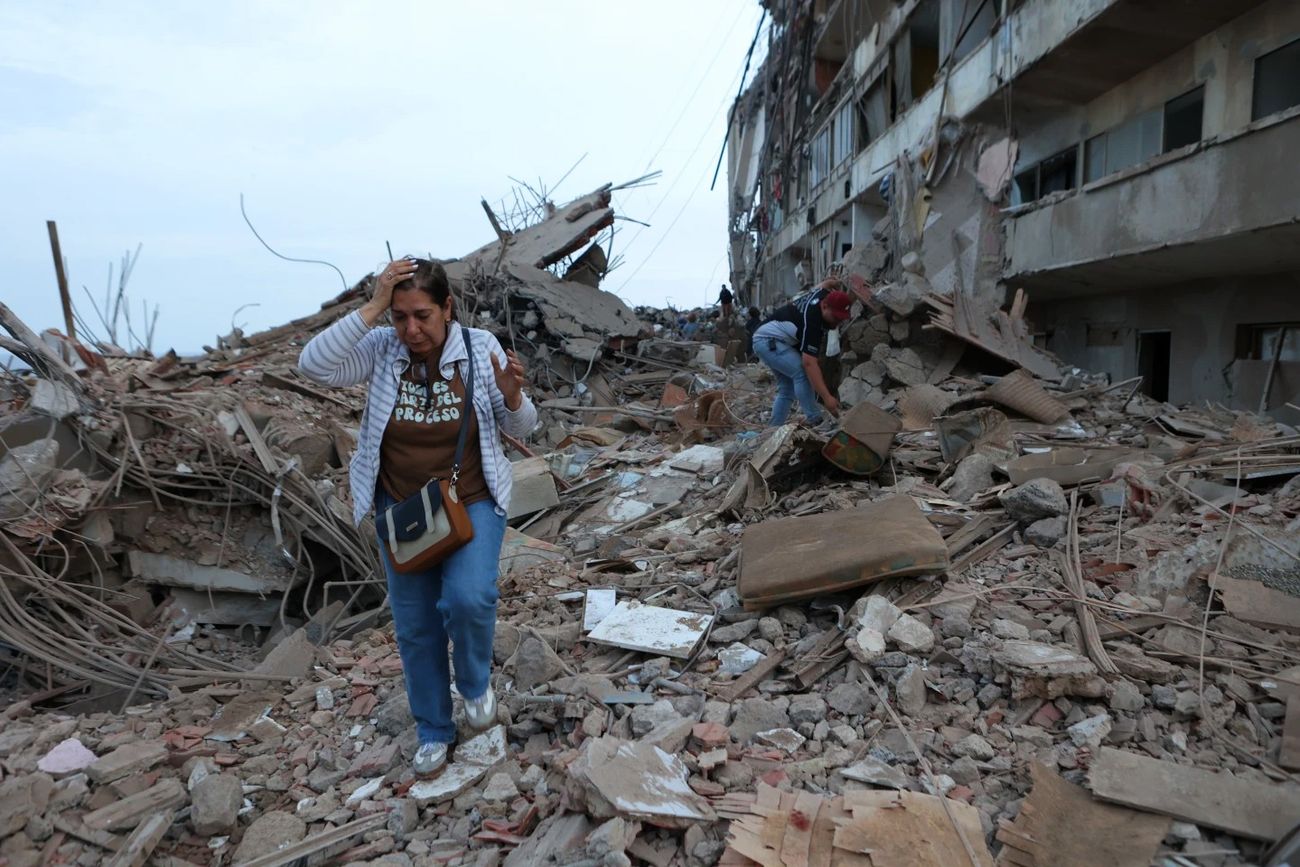 Dos mujeres caminan entre los escombros de edificios dañados por los sismos ocurridos el día anterior, el 25 de junio de 2026, en Catia La Mar, Venezuela. (Pedro Mattey)