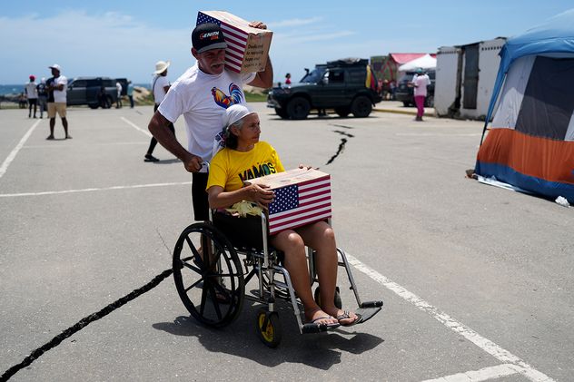 Personas afectadas por los terremotos transportan ayuda humanitaria estadounidense tras recibirla en La Guaira, Venezuela.