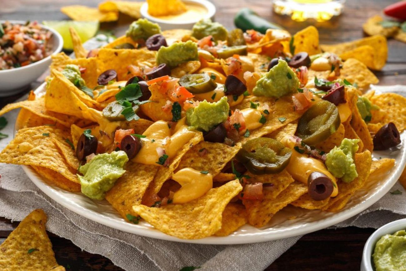 Los nachos con cheddar y guacamole son una de las picadas calientes más elegidas para compartir durante reuniones y partidos de fútbol gracias a su preparación rápida y su gran sabor.