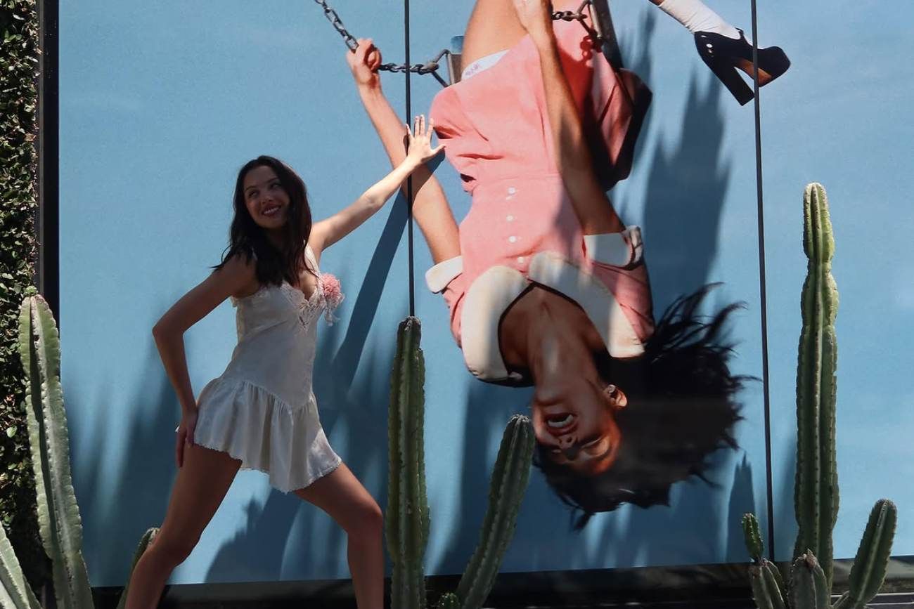 Olivia Rodrigo, frente a una gigantografía con la tapa de su nuevo disco "you seem pretty sad for a girl so in love". (Instagram @oliviarodrigo)