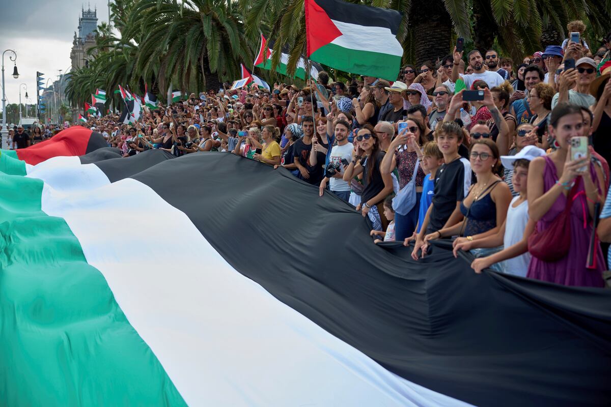La gente sostiene una bandera palestina gigante para despedir en Barcelona a la flotilla de activistas rumbo a Gaza.