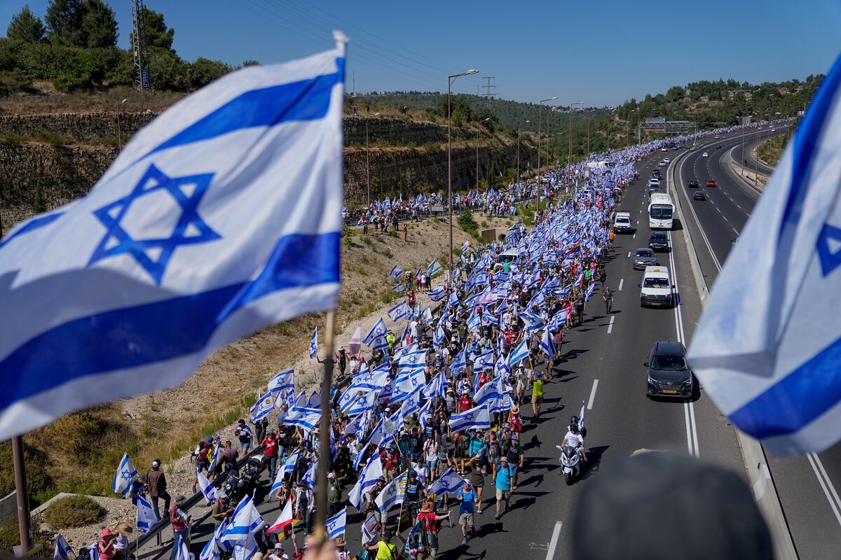 Miles de israelíes marchan por una autopista hacia Jerusalén en protesta por los planes del gobierno del primer ministro, Benjamin Netanyahu, de reformar el sistema judicial, cerca de Abu Gosh, Israel, el sábado 22 de julio de 2023. (AP Foto/Ohad Zwigenberg)