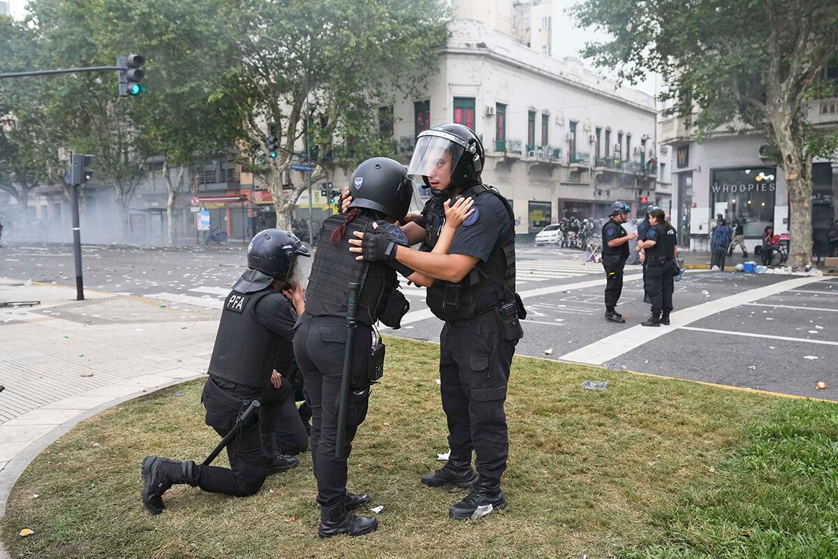 Oficial de policía sostiene a un colega en medio de enfrentamientos en la manifestación. (AP)