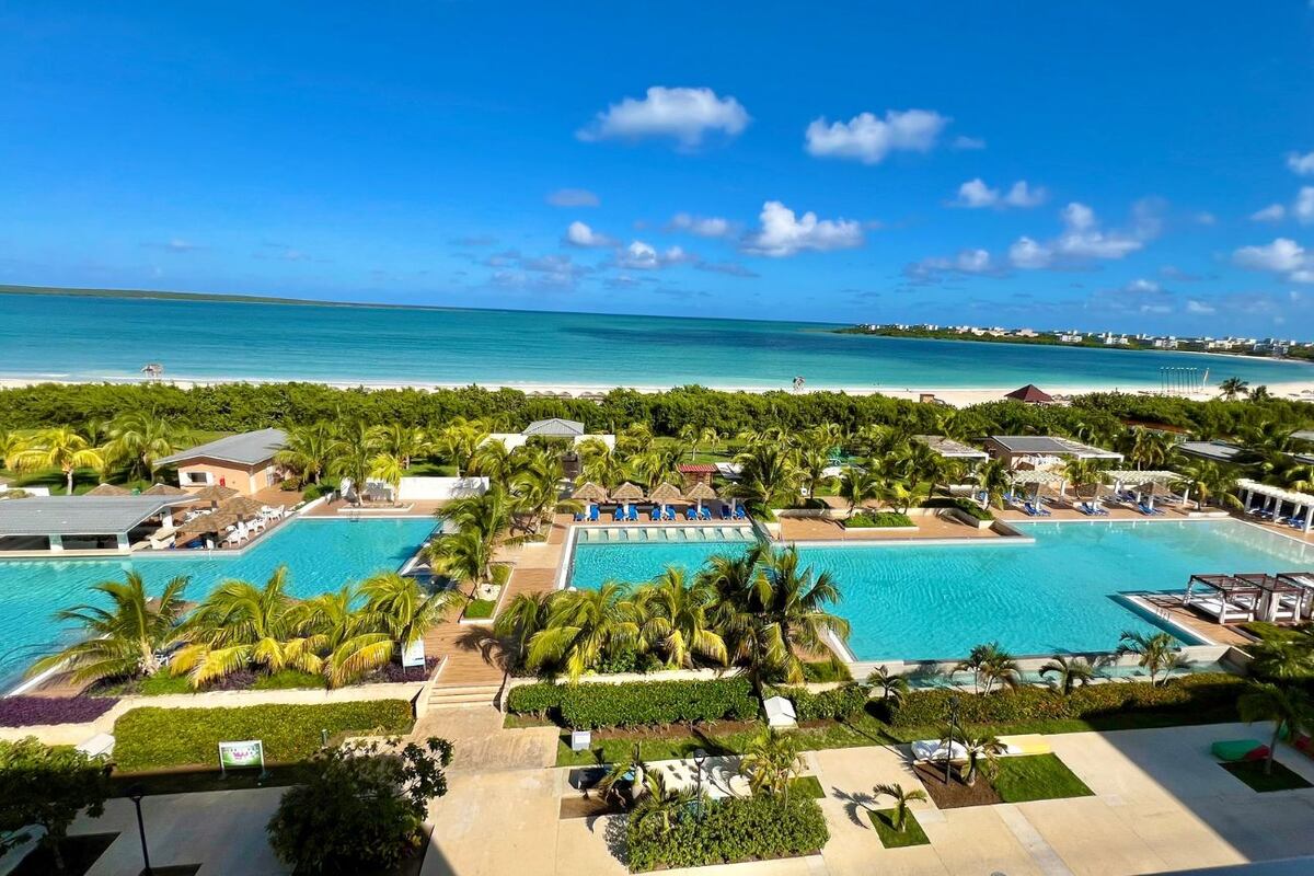 Vista desde uno de los balcones de The One Gallery Resort_ piscinas, palmeras y el mar caribeño.