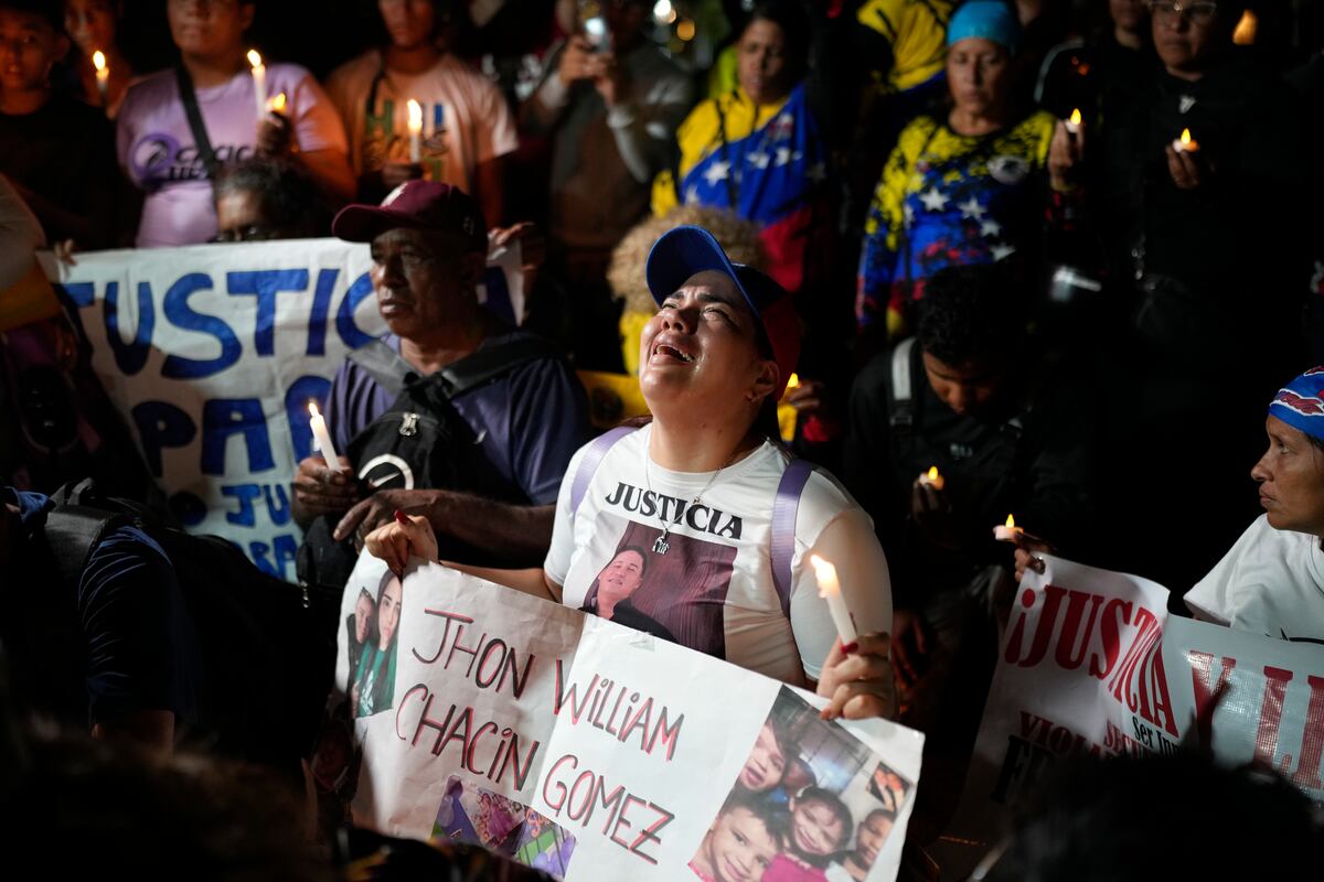 Personas con fotos de sus familiares, que fueron deportados de EEUU y trasladados a una prisión en El Salvador después de que EEUU alegara que eran miembros de la pandilla Tren de Aragua, lloran y rezan frente a la embajada salvadoreña en Caracas, Venezuela, el miércoles 2 de abril de 2025. (AP Foto/Ariana Cubillos)
