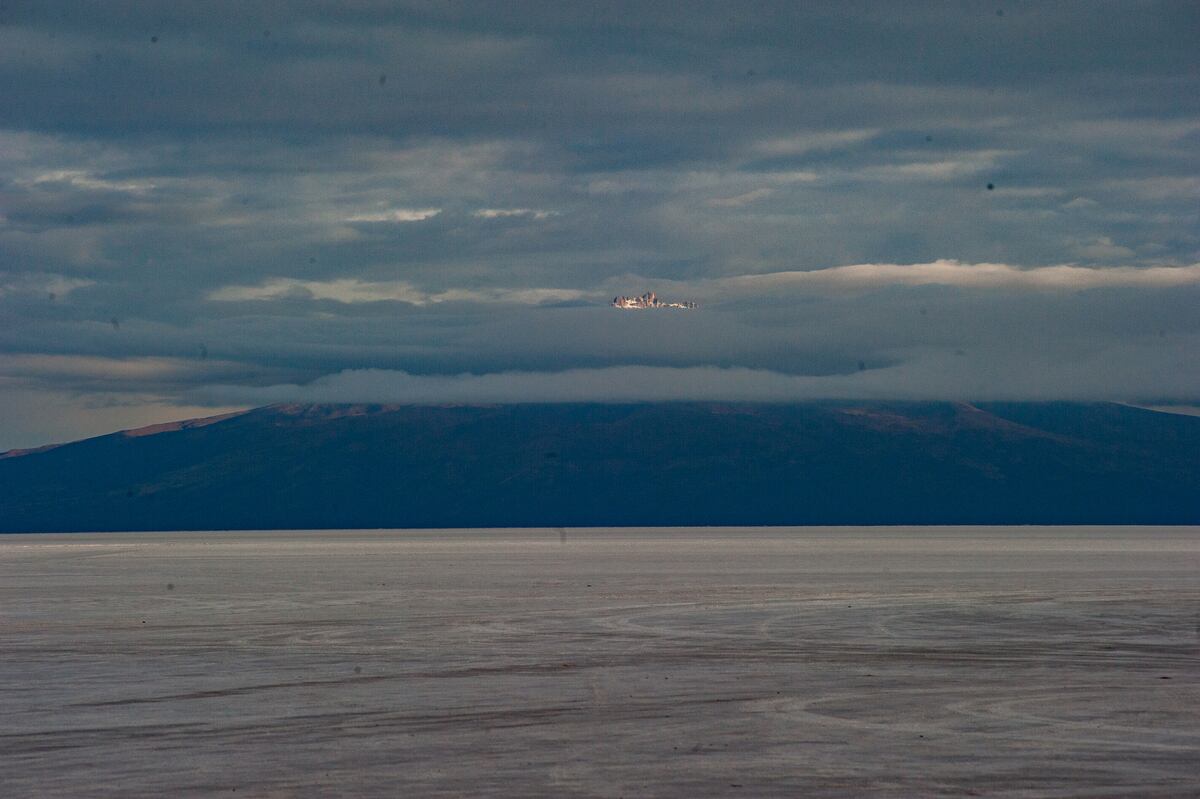 Hacia el norte, las nieves del volcán Tunupa, de 5432 metros, sobresalen sobre el mar de nubes que lo cubre, rodeada de colinas y conos oscuros.