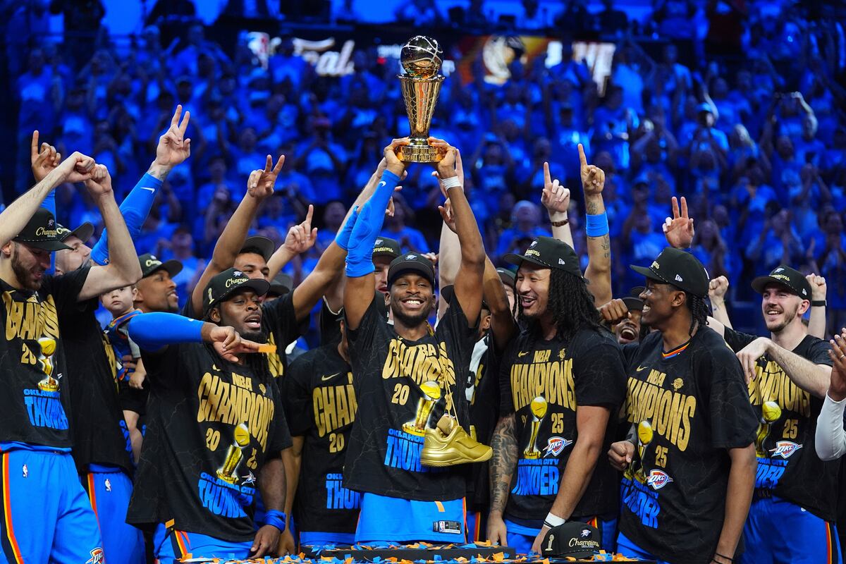 El base del Thunder de Oklahoma City Shai Gilgeous-Alexander sostiene el trofeo de MVP con sus compañeros de equipo tras ganar el título de la NBA el domingo 22 de junio del 2025. (AP Foto/Julio Cortez)