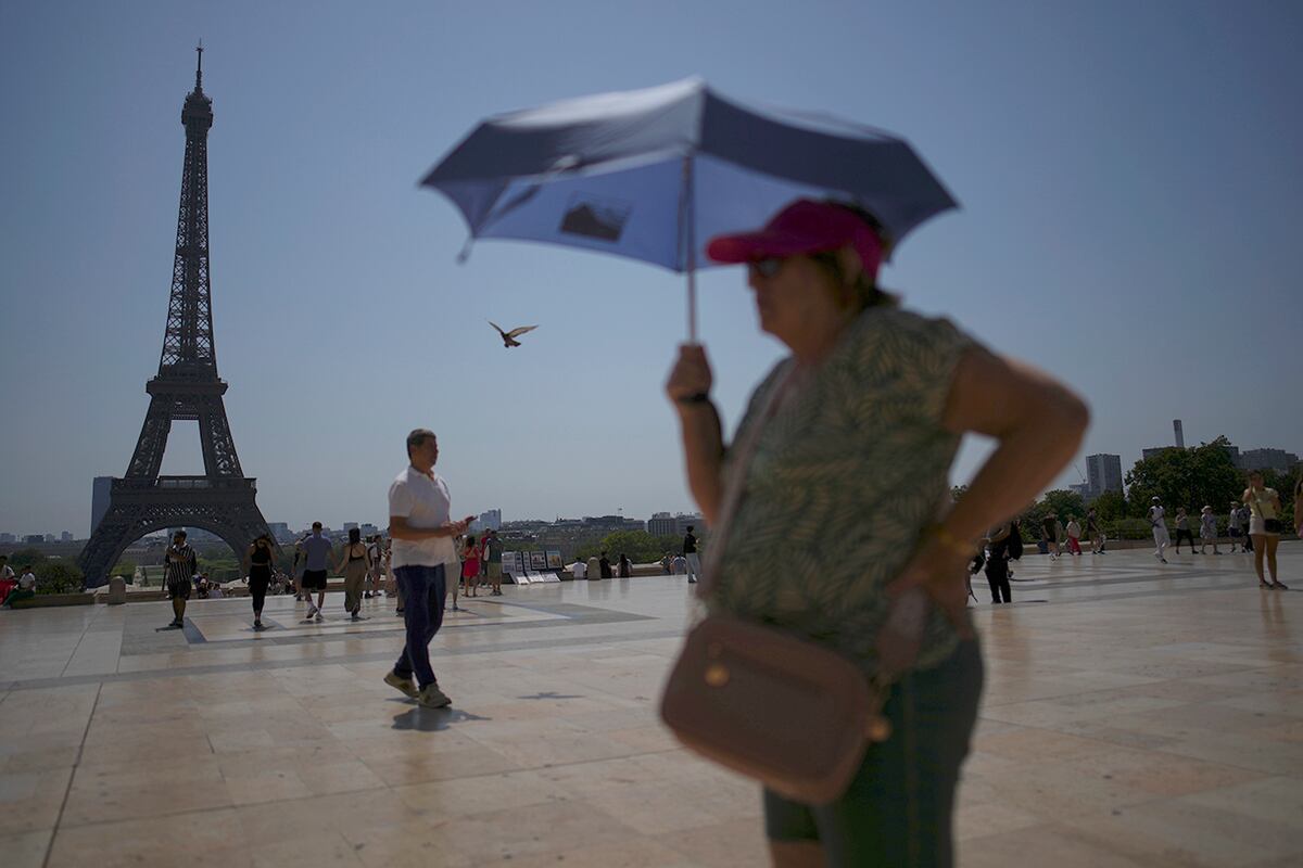 Personas caminan en la plaza del Trocadero, cerca de la Torre Eiffel, durante una ola de calor el 2 de julio de 2025 en París. (Foto AP/Christophe Ena, Archivo)