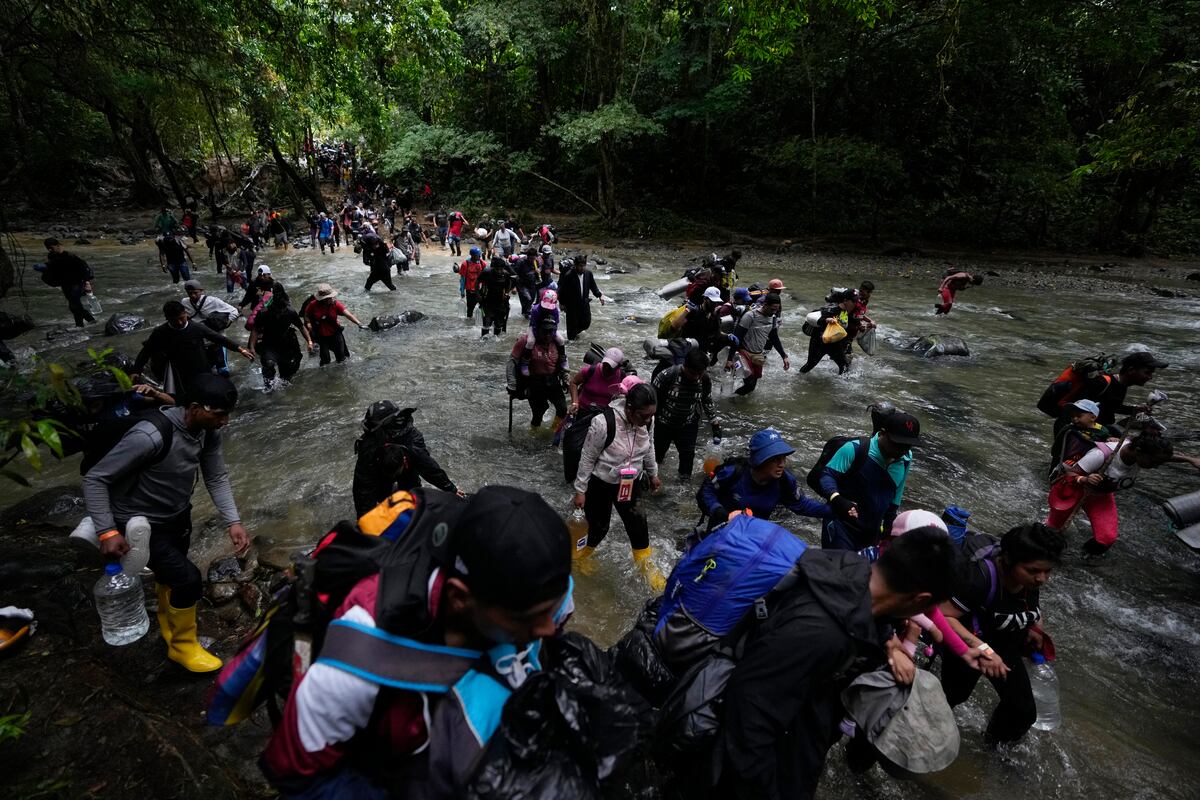 ARCHIVO - Migrantes, en su mayoría venezolanos, cruzan un río durante su viaje a través del Tapón del Darién desde Colombia a Panamá (AP Foto/Fernando Vergara, Archivo)