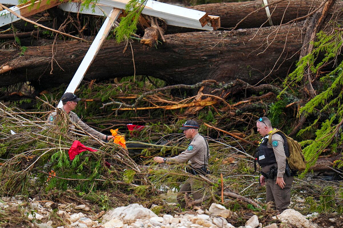 Guardabosques de Texas revisan los escombros a lo largo de las orillas del río. (AP)