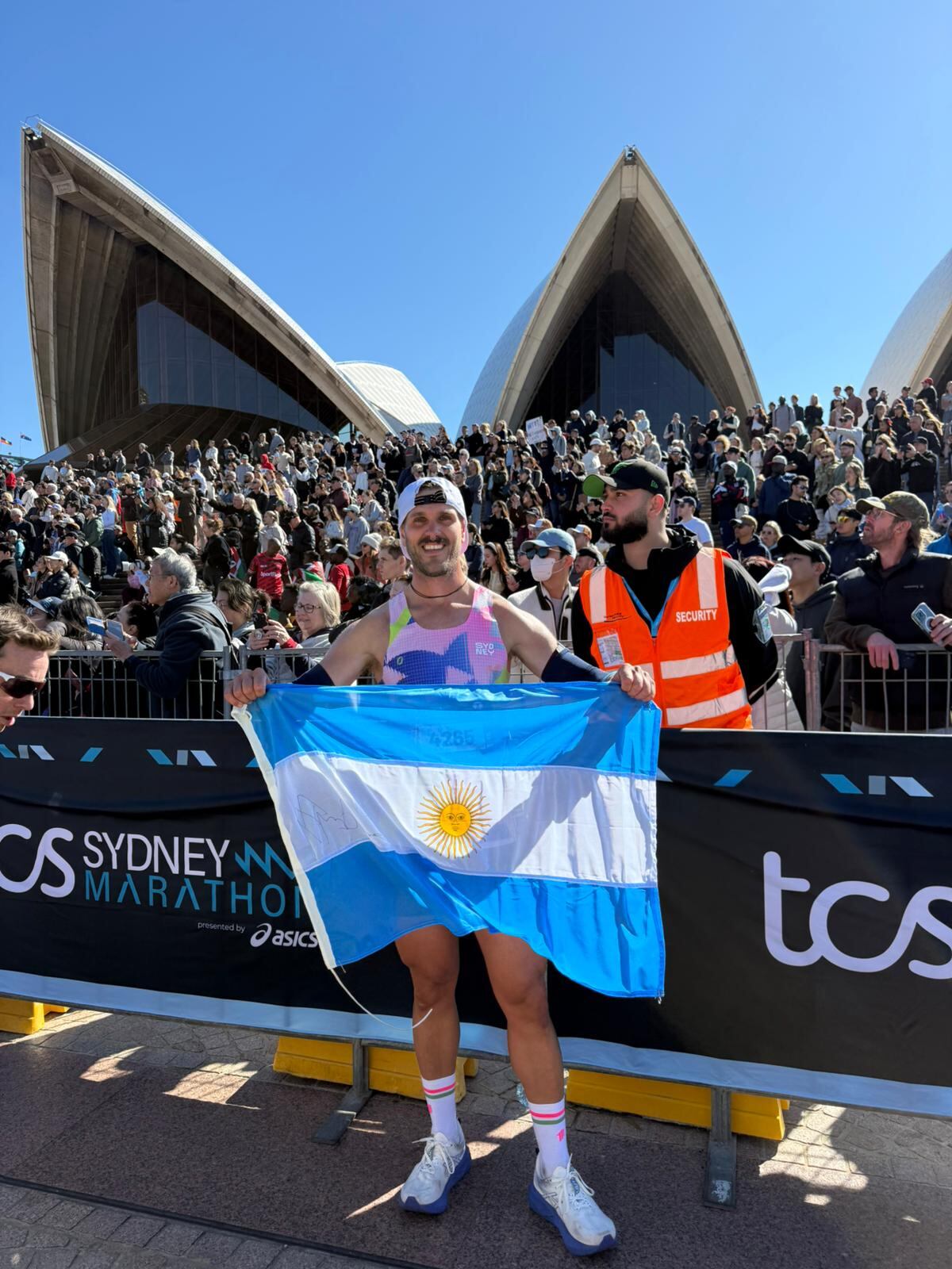 Vicente Polimeni en la línea final del Maratón de Sydney 2025, con la bandera argentina firmada por Eliud Kipchoge, que es el corredor más rápido de la historia del maratón. (Gentileza)