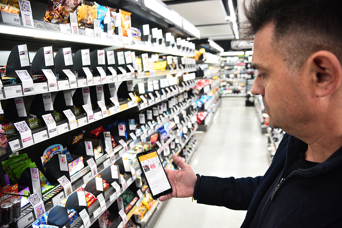 Desde el celular. En las tiendas American Vending el consumir crea su cuenta en la aplicación, desde su celular, y con ella ingresa, carga productos al carrito, paga y sale; todo escaneando códigos QR con su teléfono. Arnold lo muestra en la sucursal de Las Delicias. (Pedro Castillo / La Voz)