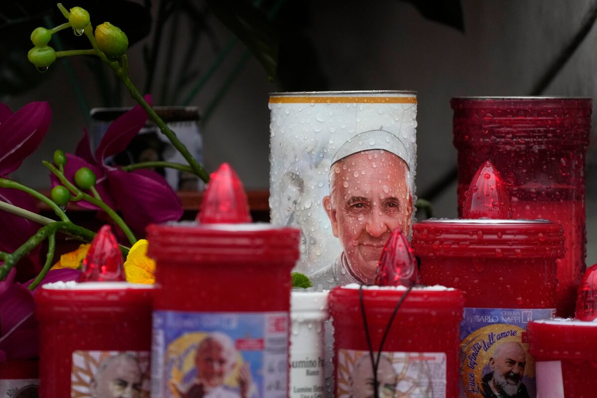 Gotas de lluvia mojan las velas con la imagen del papa Francisco depositadas en el exterior del hospital Agostino Gemelli, donde está siendo tratado por una neumonía bilateral, en Roma, el 24 de febrero de 2025. (AP Foto/Gregorio Borgia)