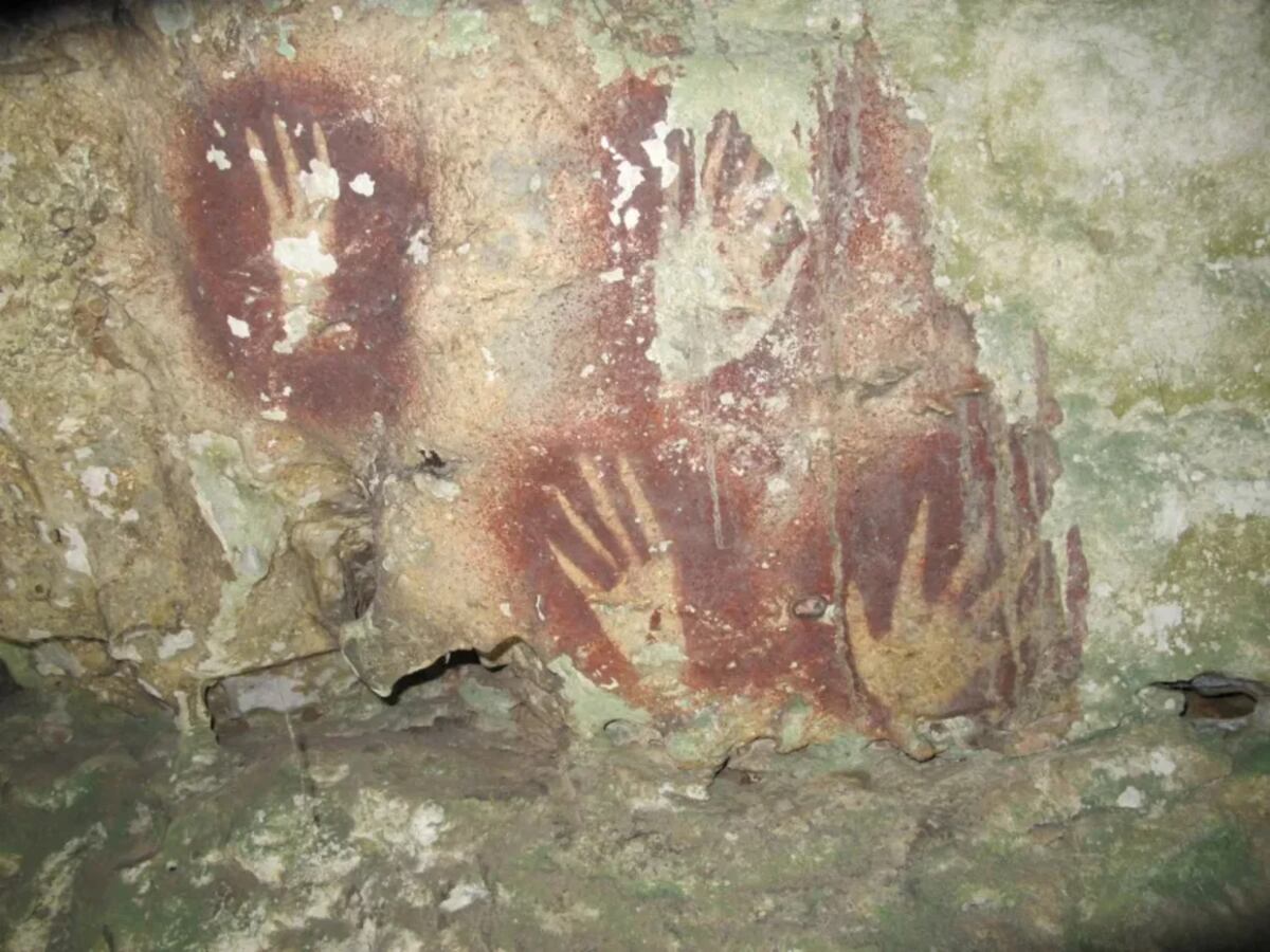 El tenue contorno de la plantilla de la mano detallada en el nuevo estudio se puede ver aquí entre otras pinturas rupestres. Universidad Griffith