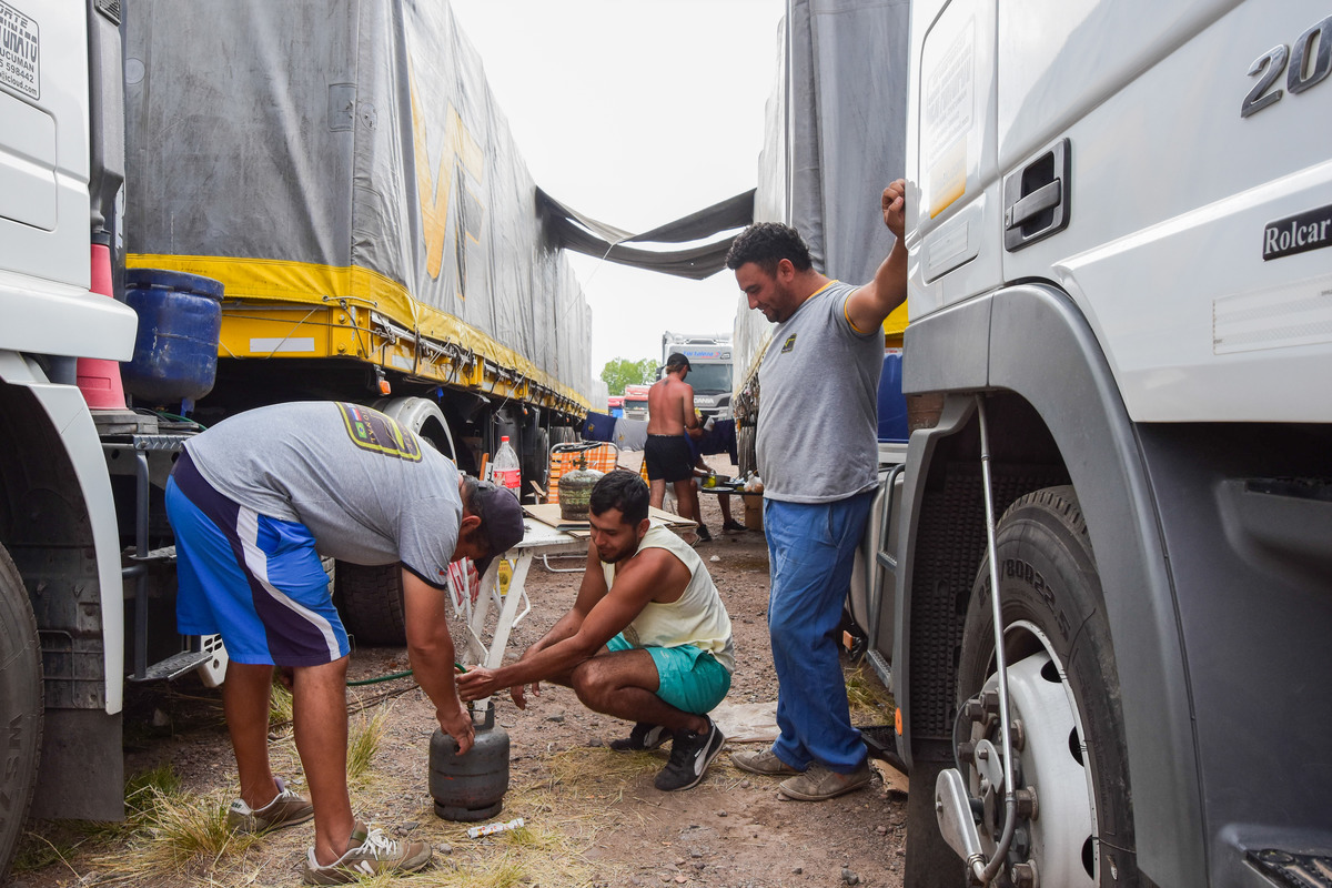 Ya hay casi 3.000 camiones varados y queda poco lugar en Mendoza: recomiendan no enviar carga a Chile. En la foto: un grupo de camioneros tucumanos comparten el almuerzo mientras realizan labores de higiene.
Foto: Mariana Villa / Los Andes