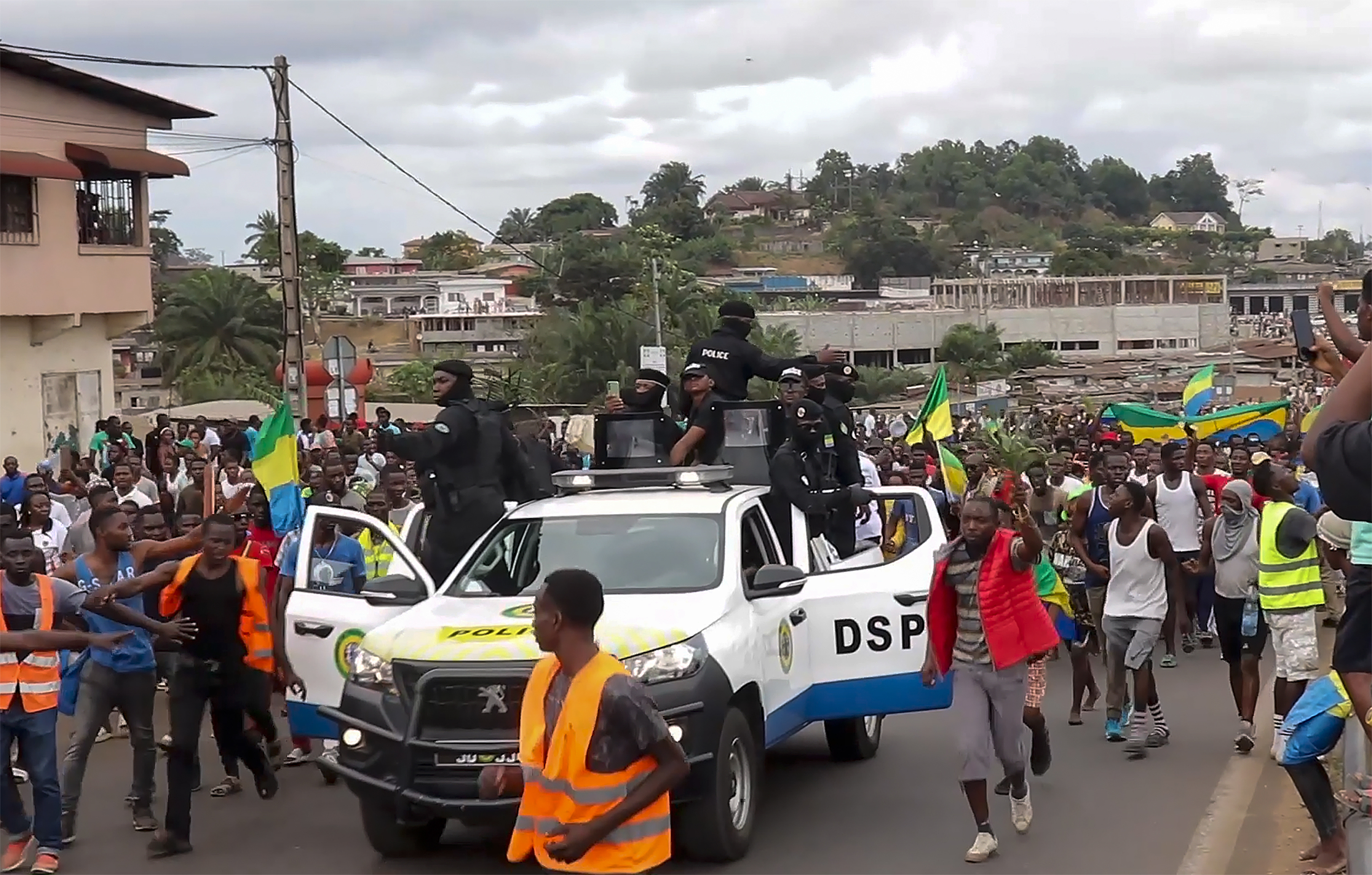ARCHIVO - La imagen tomada de un video muestra a partidarios del golpe de Estado festejando a la policía en Libreville, Gabón, 30 de agosto de 2023. Un dirigente opositor en Gabón acusó a la familia del presidente recientemente depuesto de maquinar su caída para mantener el poder en la nación de África central rica en petróleo. (AP Foto/Betiness Mackosso, File)