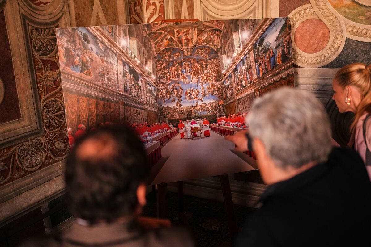 Reporteros observan una fotografía del cónclave donde fue elegido el fallecido papa Francisco el 13 de marzo de 2013, expuesta en el interior de los Apartamento Borgia, en los Museos Vaticanos, durante una visita para la prensa, el 2 de mayo de 2025. (AP Foto/Francisco Seco)